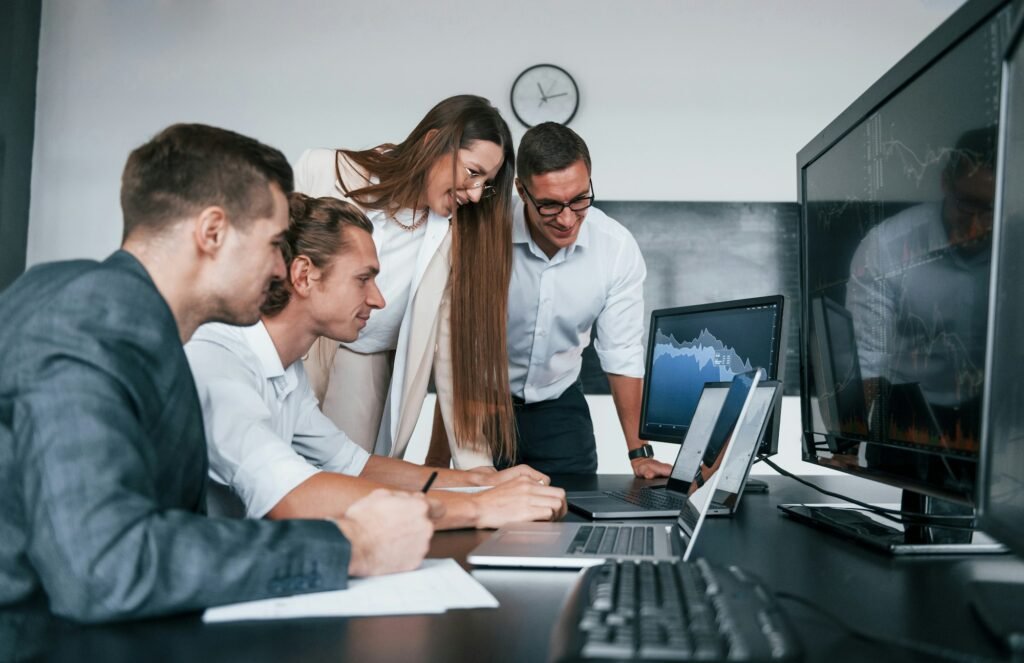 Tracks the graphs. Team of stockbrokers works in modern office with many display screens