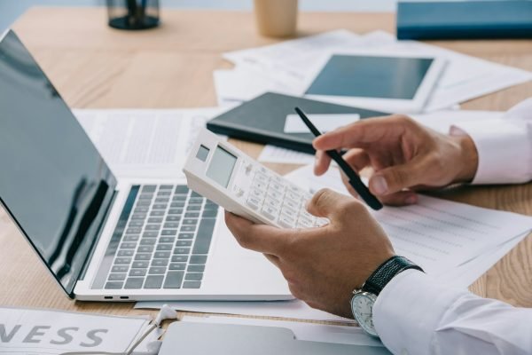 cropped shot of businessman making calculations at workplace with papers