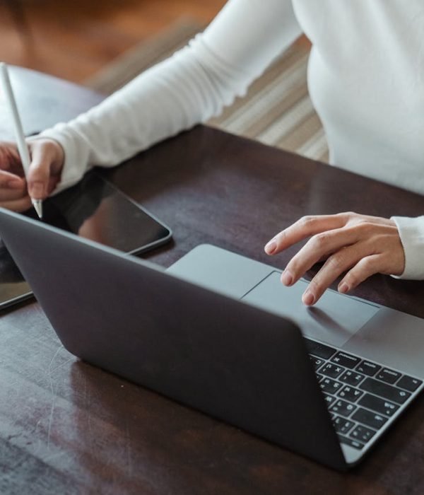 Crop faceless female entrepreneur doing multitasking work on different devices